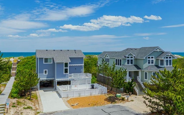 view of front of home with a water view, fence, stairway, concrete driveway, and a carport