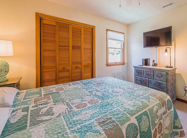 carpeted bedroom with visible vents, a closet, and a textured ceiling