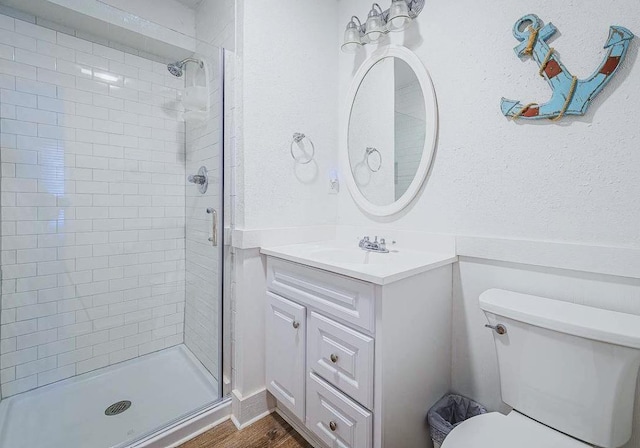 full bathroom with wood finished floors, toilet, a stall shower, and vanity