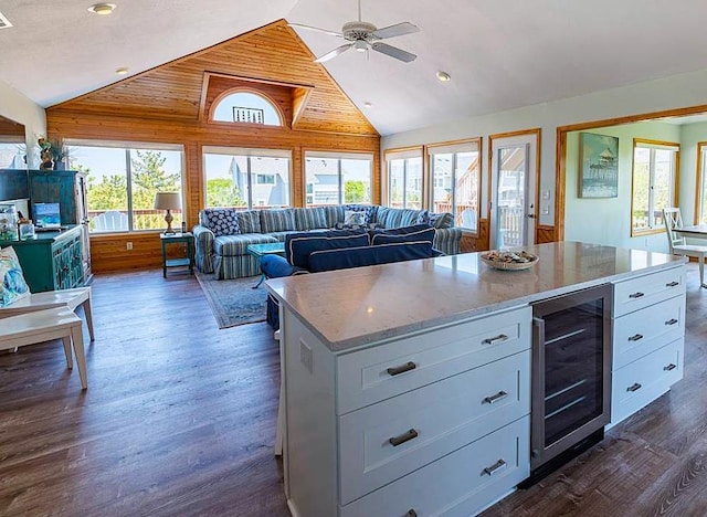 kitchen with light stone counters, dark wood-style flooring, wine cooler, white cabinetry, and open floor plan