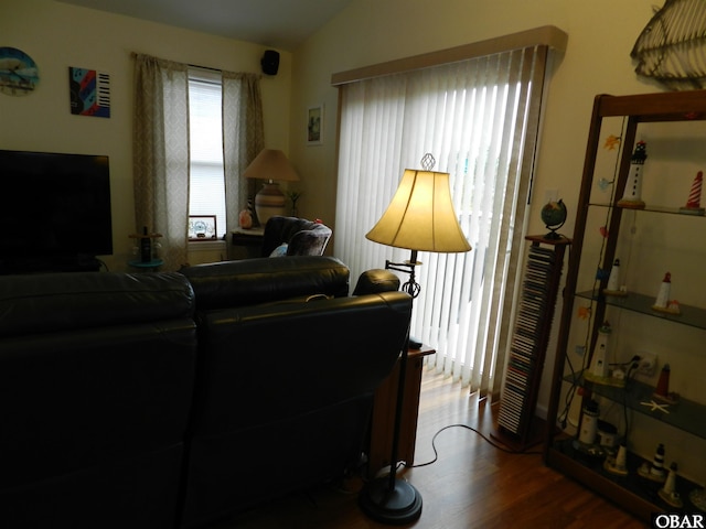 living area with vaulted ceiling, wood finished floors, and a healthy amount of sunlight