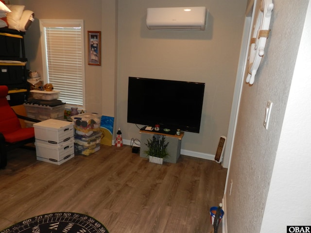 living room with wood finished floors, baseboards, and a wall mounted AC