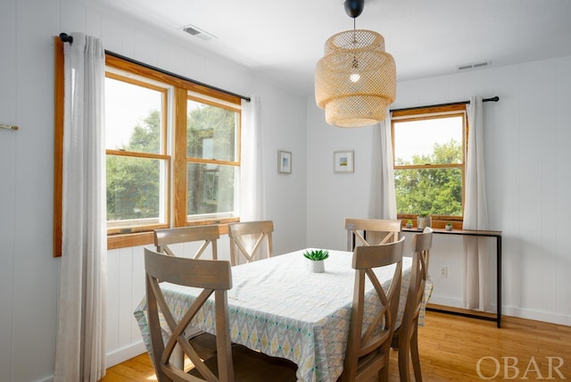 dining room with light wood-type flooring, visible vents, and a wealth of natural light