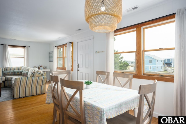 dining area with light wood finished floors, visible vents, and crown molding