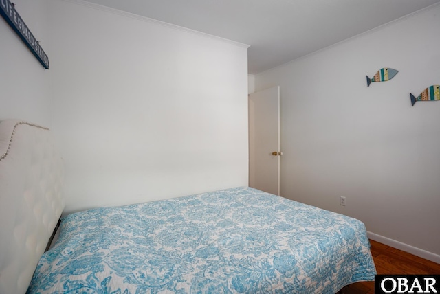 bedroom with ornamental molding, baseboards, and wood finished floors