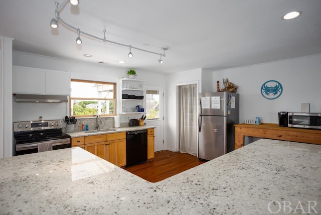 kitchen with light stone countertops, appliances with stainless steel finishes, extractor fan, and a sink