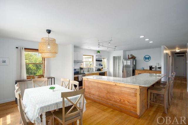 kitchen with light stone countertops, white cabinetry, appliances with stainless steel finishes, and light wood-style floors