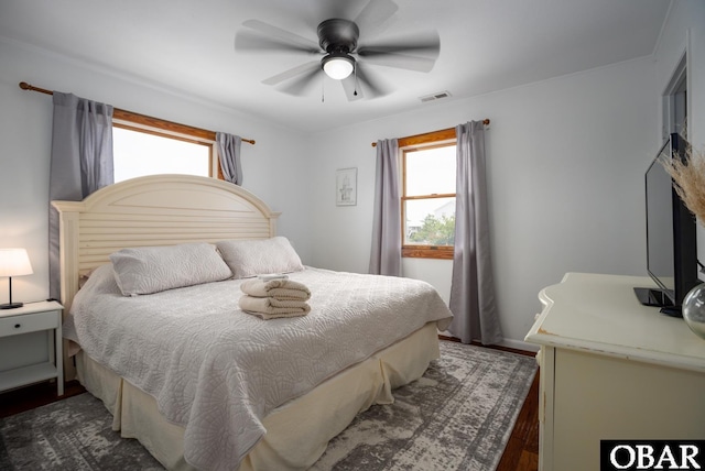 bedroom featuring a ceiling fan, dark wood-style flooring, visible vents, and multiple windows