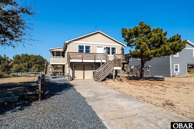 beach home with board and batten siding, concrete driveway, and stairs