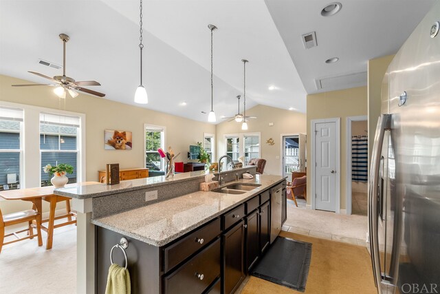 kitchen featuring freestanding refrigerator, visible vents, a sink, and dark brown cabinets