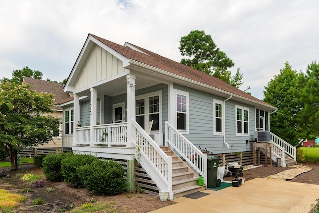 view of front of property with board and batten siding, a porch, a shingled roof, and central AC unit