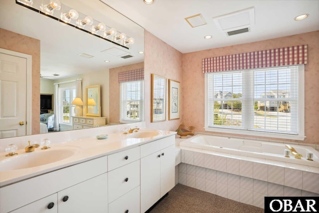 ensuite bathroom with a garden tub, ensuite bathroom, visible vents, and a sink