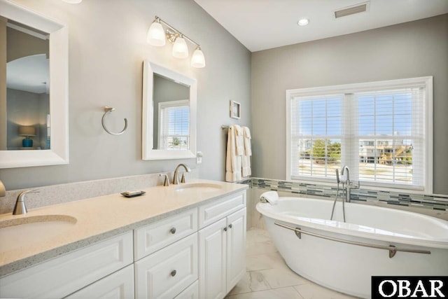 full bathroom featuring a freestanding tub, visible vents, marble finish floor, and a sink