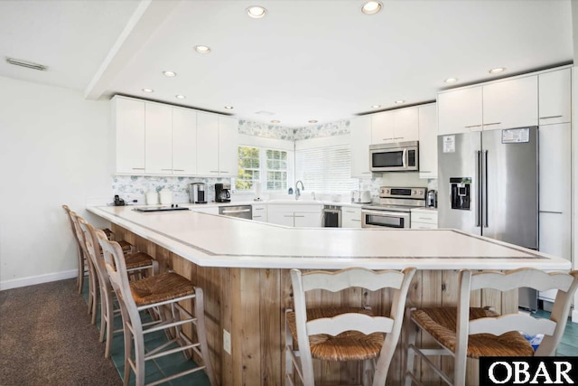 kitchen with a breakfast bar, a sink, recessed lighting, and appliances with stainless steel finishes