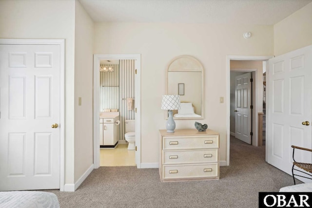 bedroom with ensuite bath, baseboards, carpet floors, and a chandelier
