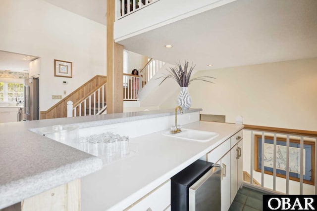 kitchen featuring recessed lighting, light countertops, a sink, freestanding refrigerator, and white cabinetry