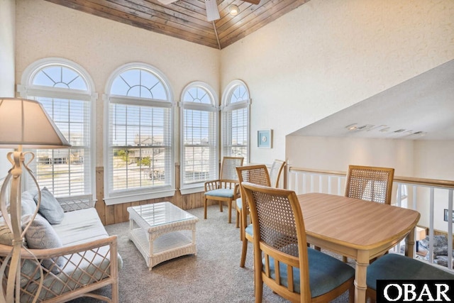 carpeted dining area featuring high vaulted ceiling, wood ceiling, and ceiling fan