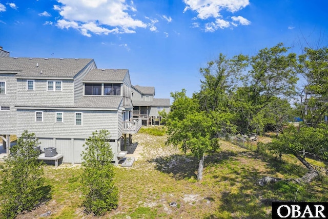 rear view of property featuring fence and roof with shingles