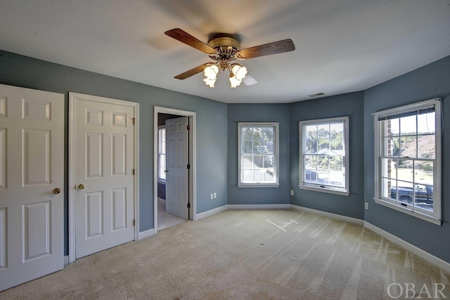 unfurnished bedroom featuring light colored carpet, visible vents, baseboards, and multiple windows