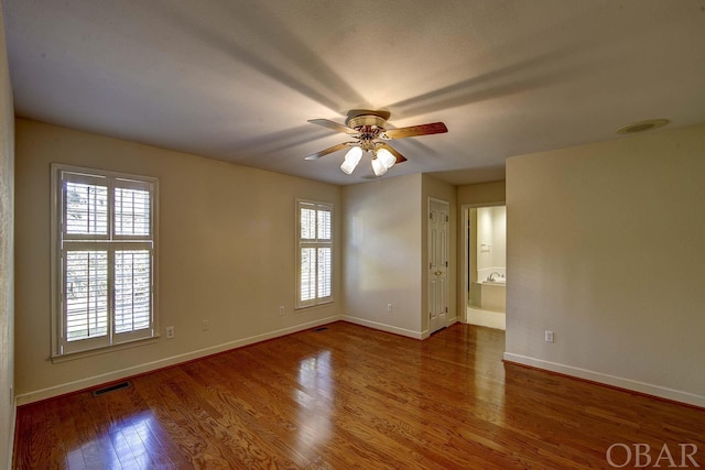 spare room with ceiling fan, wood finished floors, visible vents, and baseboards