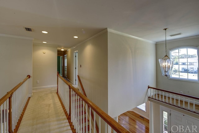 hall featuring visible vents, ornamental molding, and an upstairs landing