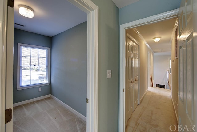 corridor featuring ornamental molding, light carpet, visible vents, and baseboards