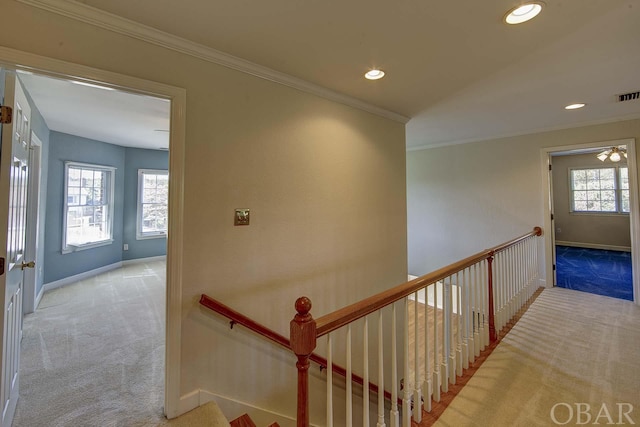 hall with a wealth of natural light, light colored carpet, and an upstairs landing