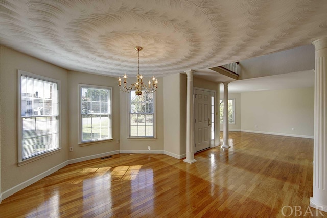 unfurnished dining area with light wood-type flooring, visible vents, decorative columns, and baseboards