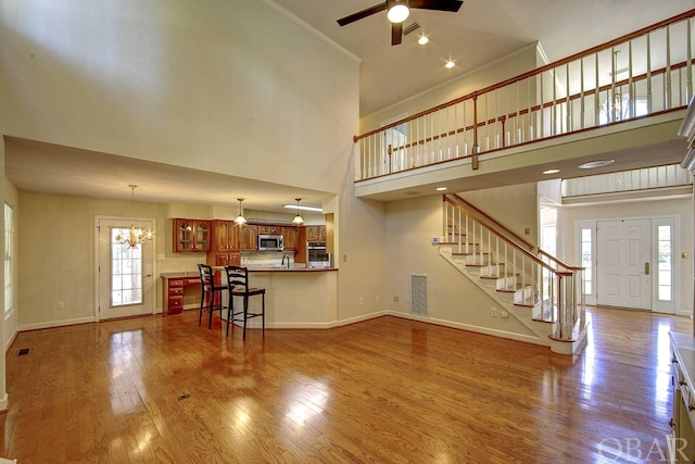 unfurnished living room featuring ornamental molding, stairway, light wood-type flooring, and baseboards