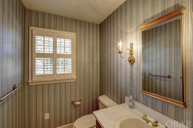 bathroom featuring vanity, toilet, and wallpapered walls