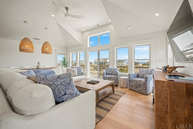 living area with recessed lighting, visible vents, light wood-style flooring, a ceiling fan, and high vaulted ceiling