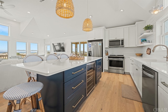 kitchen featuring beverage cooler, stainless steel appliances, a sink, and white cabinetry