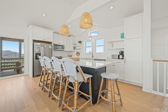 kitchen featuring appliances with stainless steel finishes, hanging light fixtures, light countertops, white cabinetry, and open shelves