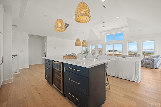 kitchen with wine cooler, visible vents, open floor plan, light countertops, and a kitchen bar