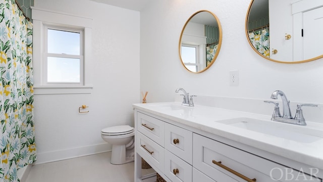 bathroom with double vanity, baseboards, toilet, and a sink