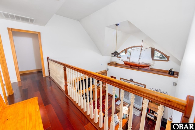 hall featuring lofted ceiling, visible vents, dark wood finished floors, and an upstairs landing