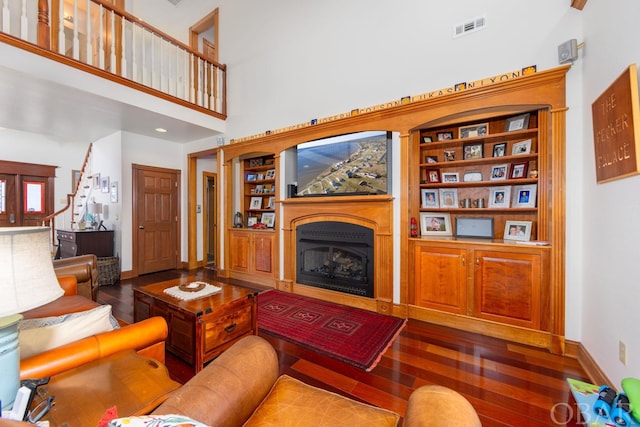 living room featuring baseboards, a fireplace, visible vents, and dark wood-type flooring