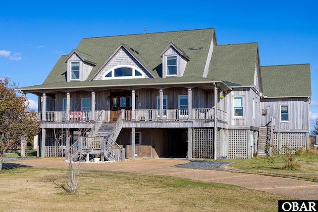 view of front facade with roof with shingles, a porch, stairway, and a front lawn