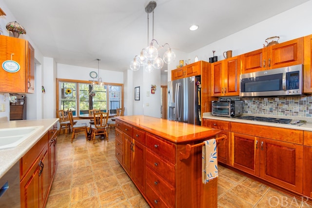 kitchen with light countertops, appliances with stainless steel finishes, decorative light fixtures, and decorative backsplash