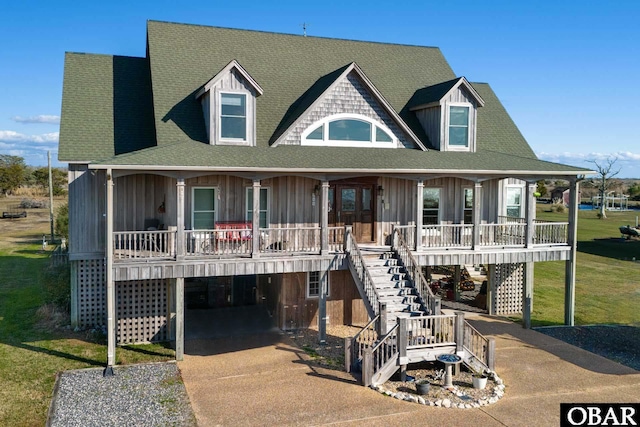 view of front of house with concrete driveway, roof with shingles, stairs, a porch, and a carport