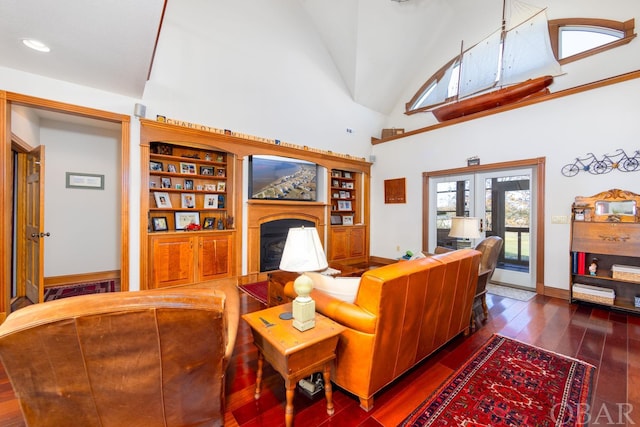 living area with baseboards, dark wood-style floors, french doors, a fireplace, and high vaulted ceiling