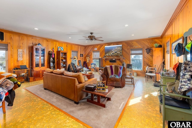 living area with ceiling fan, wooden walls, crown molding, and recessed lighting