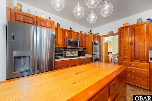 kitchen featuring pendant lighting, brown cabinets, stainless steel appliances, backsplash, and butcher block countertops