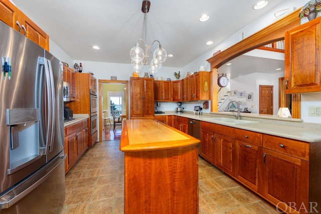 kitchen with decorative light fixtures, stainless steel refrigerator with ice dispenser, wooden counters, a kitchen island, and a sink