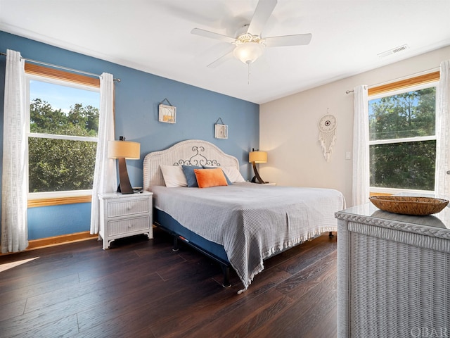 bedroom with dark wood-style floors, ceiling fan, multiple windows, and visible vents