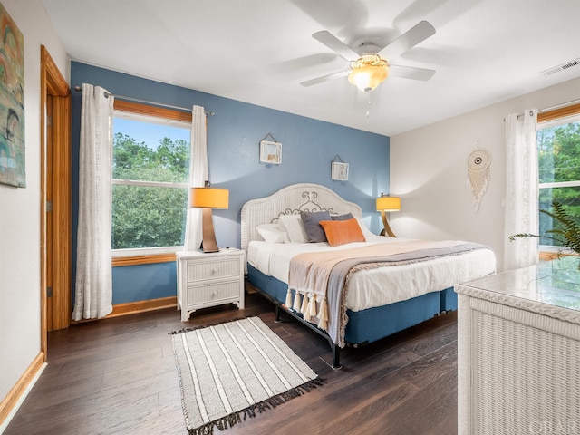 bedroom featuring dark wood-style floors, visible vents, baseboards, and a ceiling fan