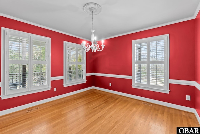 unfurnished room with a chandelier, visible vents, crown molding, and wood finished floors