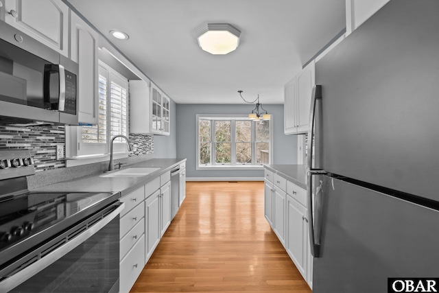 kitchen with appliances with stainless steel finishes, white cabinets, a sink, and decorative backsplash