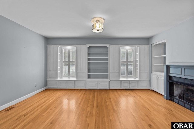 unfurnished living room featuring light wood-style floors, visible vents, a fireplace, and baseboards