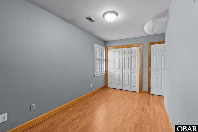 unfurnished bedroom with light wood-style floors, a closet, visible vents, and baseboards